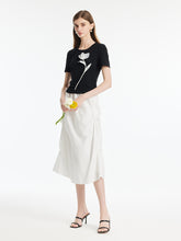 A lady wears a white skirt and a black T-shirt.